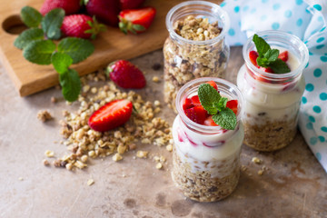 Homemade healthy breakfast with homemade baked granola, fresh strawberry and yogurt on stone or concrete table. Copy space.