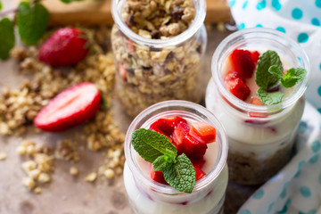 Homemade healthy breakfast with homemade baked granola, fresh strawberry and yogurt close-up on stone or concrete table.