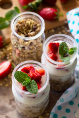 Homemade healthy breakfast with homemade baked granola, fresh strawberry and yogurt close-up on stone or concrete table.