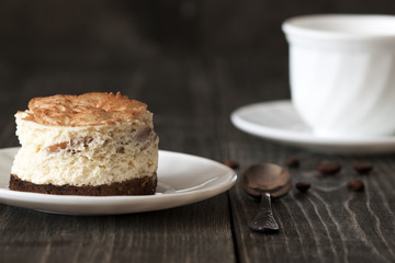 Tiramisu cake on a white saucer and a cup of black coffee