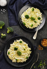 American delicious mac and cheese with creamy sauce and broccoli on black dishes. Top view with close -up.