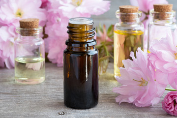 A bottle of essential oil with pink kwanzan cherry blossoms