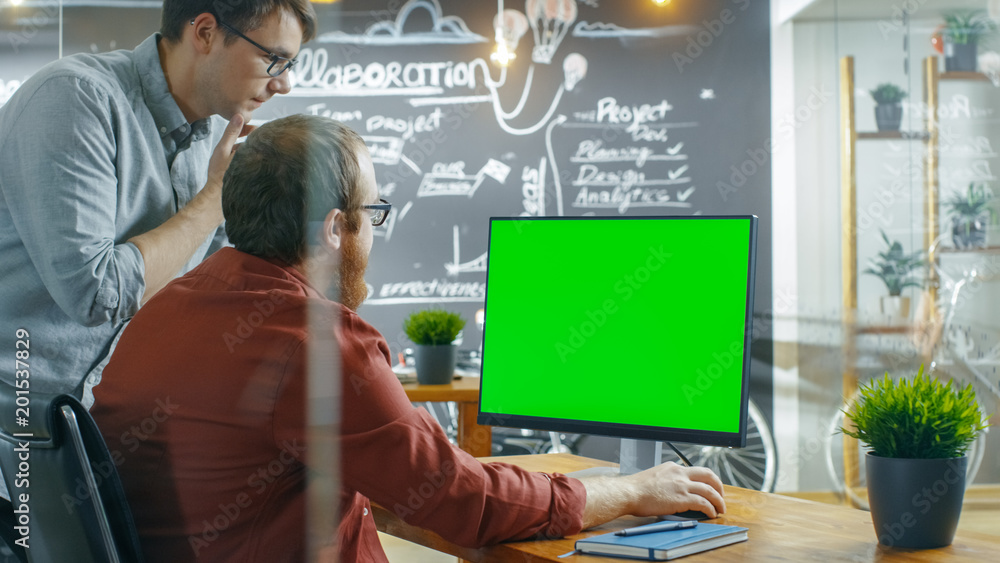 Aufkleber Two Male Developers Talk about Project, while Personal Computer Has Green Mock-up Screen. They Work in the Creative Agency.
