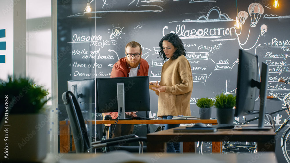 Poster female designer talks with male developer, they look at personal computer screen. in the background 