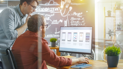 Two Male Mobile Game Application Developers Talk while Working on a Personal Computer, Designing...