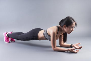 Fototapeta na wymiar Young beautiful lady fitness training by planking on the floor