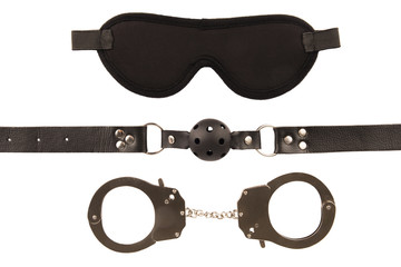 Blindfold mask, handcuffs and a ball gag, isolated on white background.