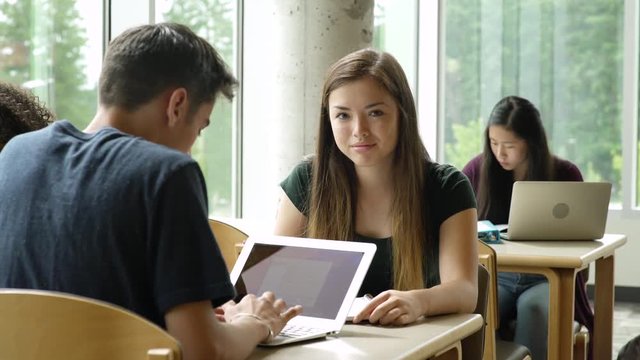 Female student looking at camera while studying at a table