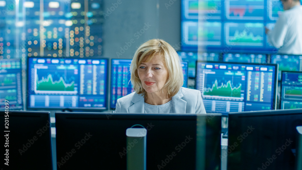 Poster in the market exchange room senior sales force representative works at her workstation. in the backg