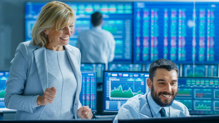 Stock Market Team Wins Big on Selling/ Buying Bonds. Senior Manager and Professional Trader are Happy. Ticker Numbers on Screen.