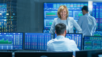 In the Stock Market Selling/ Buying Department Female Manager Talks with Male Trader and Smiles. In...