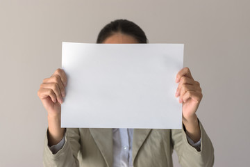 A woman holds blank sign in front her face