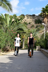 Fototapeta na wymiar Two young guys ride on mono wheels in the natural park of Mount Ifach on the Costa Blanca on Mediterranean Sea