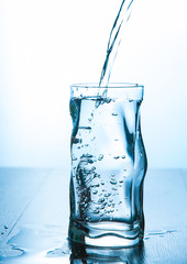 Close up pouring purified fresh drink water from the bottle in glass  with copy space