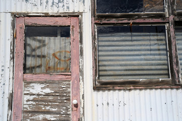 An abandoned building made of wood and corrugated metal sits in a state of decay.