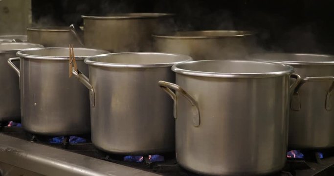 Pots boiling pierogies in an industrial kitchen or cafeteria.	 	