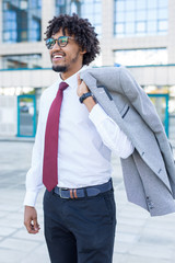 Handsome young business man smiling and holding his suit over his shoulder