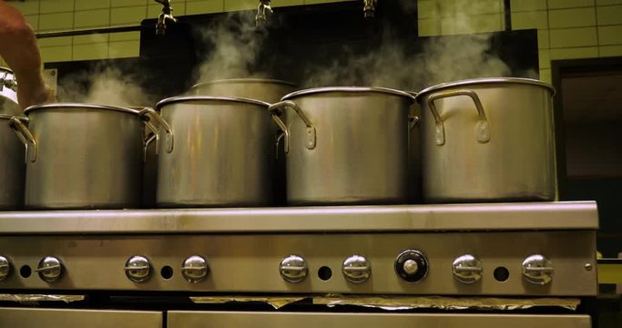 Pots boiling pierogies in an industrial kitchen or cafeteria.	 	
