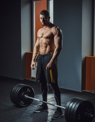 Naklejka premium european caucasian athletic man waiting and preparing before lifting heavy barbell looking at camera. . deadlift with barbell. bent over the barbell. posing in gym