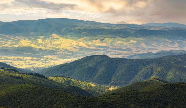 sun lit valley in afternoon. beautiful mountainous landscape and cloudy sky in golden light. lovely scenery after the storm. view from the top of a hill