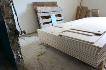 A pack of plasterboard is on the construction site in a room prepared for repair and decoration of a dwelling
