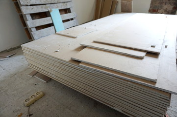 A pack of plasterboard is on the construction site in a room prepared for repair and decoration of a dwelling