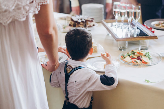 little boy eating food appetizers on table at wedding reception. luxury catering at celebrations. serving food and drinks at events concept
