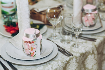 beautiful decorated setting on centerpiece table with stylish plate, glasses and cutlery at luxury wedding reception in restaurant. gift for guest. wedding favors. stylish decor and catering