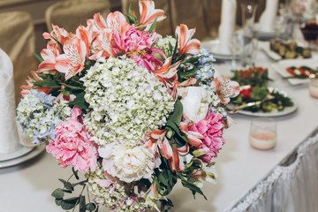 beautiful decorated centerpiece table with hydrangea bouquets in vases and greenery at luxury wedding reception in restaurant. stylish decor and adorning