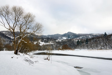 Winter landscape. Snow-covered mountain river at the foot of the high  Mountains.