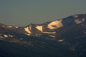 Snow on top of the mountain. Complete absence of vegetation. Evening time.