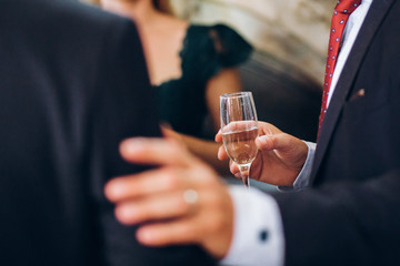 group of elegant people holding glasses of champagne at luxury wedding reception. people toasting and cheering with drinks at social events.  christmas celebration