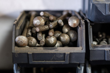 Metal screws in storage containers. Shelf locksmith workshop with parts for mechanical repairs.