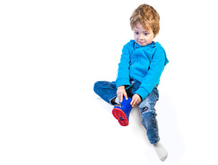 A little child of three years tries to wear shoes. Isolated on a white background