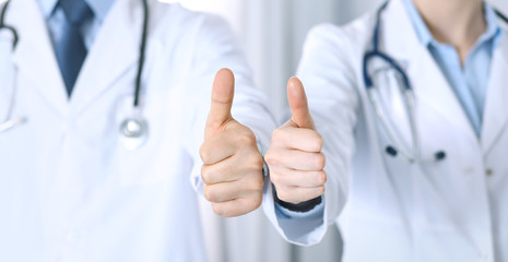 Team of unknown medicine doctors showing OK sign with thumb up close up. Success and high level service in health care, best treatment and customer loyalty and physical concept