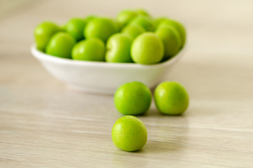 A bowl of fresh green plums on table