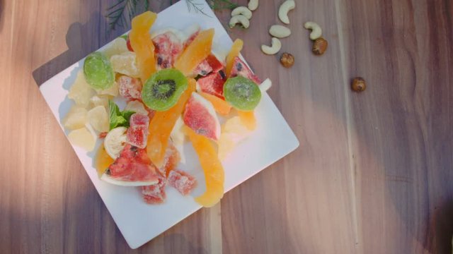Children's hand take candied fruits from the white plate
