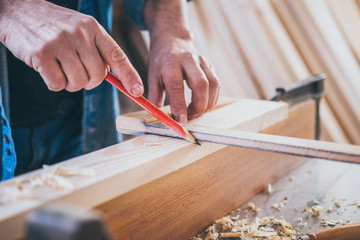 Close up of Carpenter constructing and measuring wood. Marking with carpenter pen.