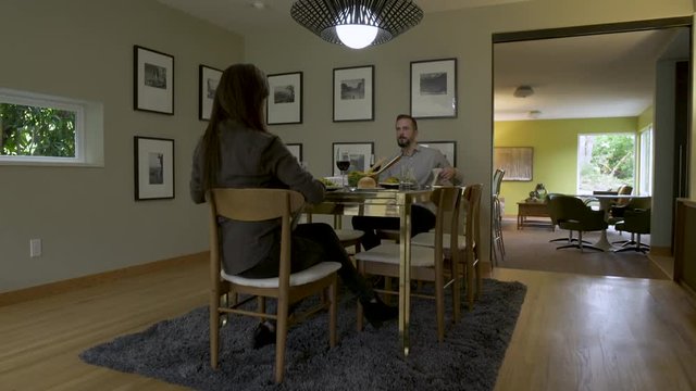 Mature couple eating meal in open plan dining room. 