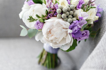 Obraz na płótnie Canvas Brides wedding bouquet with peonies, freesia and other flowers on black arm chair. Light and lilac spring color. Morning in room