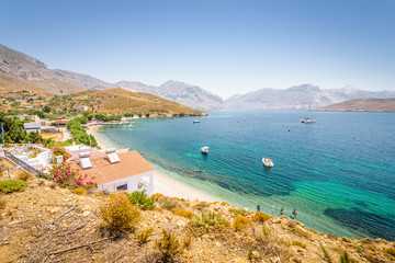 Beautiful sunny holiday coast view to the greek blue sea with crystal clear water beach relaxing with some boats fishing cruising surrounded by hills mountains, Patmos, Kos Island, Dodecanese, Greece