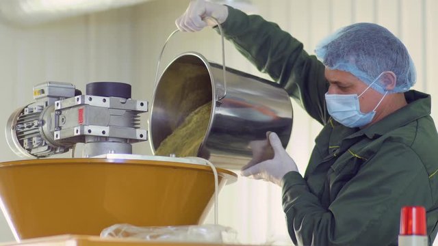 Worker pour out the tea into machine at factory