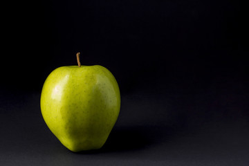 A green apple on a black background