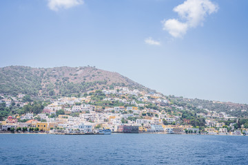 Fototapeta na wymiar Beautiful sunny greek village town harbor view to the aegean blue sea with crystal clear water boats cruising surrounded by hills mountains windmills, Agia Marina, Leros, Dodecanese Islands, Greece