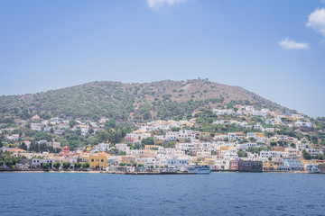 Beautiful sunny greek village town harbor view to the aegean blue sea with crystal clear water boats cruising surrounded by hills mountains windmills, Agia Marina, Leros, Dodecanese Islands, Greece