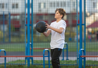 cute young sporty boy in white t shirt plays basketball on his free time, holidays, summer day. Sport  health lifestyle concept