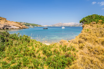 Beautiful sunny coast view to the greek blue sea with crystal clear water beach with some boats fishing cruising surrounded by hills, Kokkina Beach, Leros, Dodecanese Islands/ Greece – July 18 2017