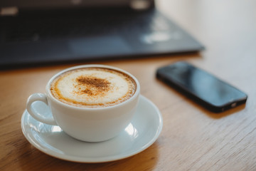 Coffee cup, laptop and smartphone on the wood table in cafe. Business concept