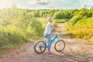 Fototapeta premium Happy child riding bike. Young girl on bicycle in sunny summer park. Healthy school children summer activity. Kids playing and cycling outdoors. Little girl learns to keep balance while riding bicycle