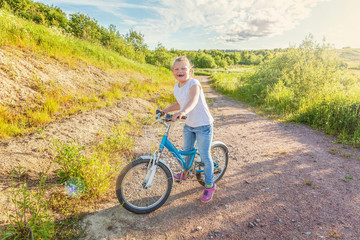 Fototapeta premium Happy child riding bike. Young girl on bicycle in sunny summer park. Healthy school children summer activity. Kids playing and cycling outdoors. Little girl learns to keep balance while riding bicycle